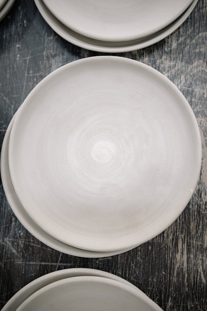 Top view of empty white ceramic plates arranged on a textured wooden surface.